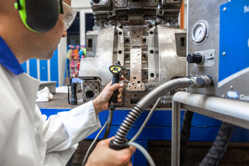 Engineer doing maintenance on a injection mold for plastic components, industrial and automotive...