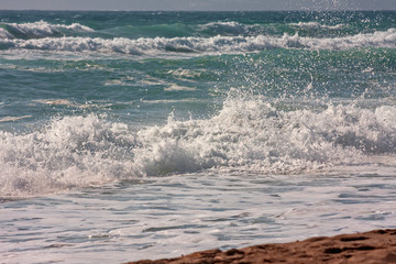 The foaming waves of the rough sea break on the beach.