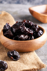 prunes, dried plums in a wooden bowl on a gray background Rustic style