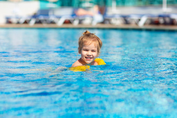 Fototapeta na wymiar little girl is swimming in the pool in armbands.