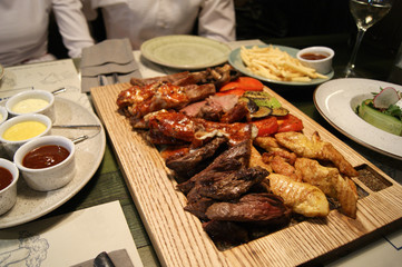 Table with a board of various cooked meat, salads and sauces