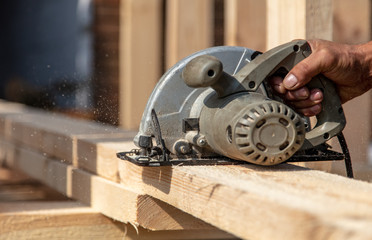 A worker saws a wooden beam.
