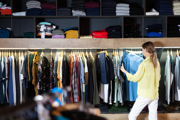 Glad woman shopping casual clothes in men store