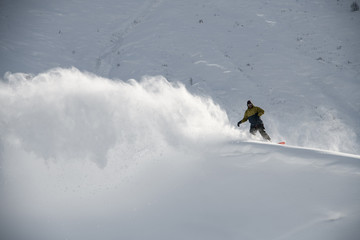 Male snowboarder slides on a snowboard in distance