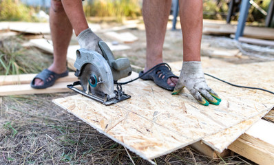 A worker saws a wooden beam.