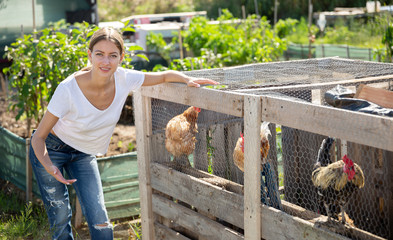 Farmer woman feeding chikens in a hen house © JackF