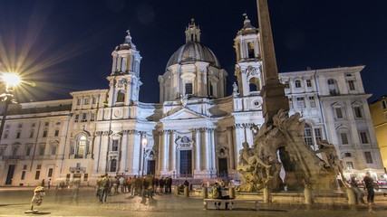 Fototapeta na wymiar Illuminated at night the fontana of the Four Rivers timelapse on Piazza Navona on the Sant'Agnese in Agone church background, Rome, Italy