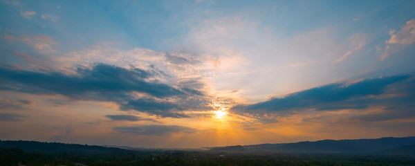 Beautiful sunset sky and dark clouds with mountain, Gorgeous panorama scenic of the Twilight sky and sun rays, with silver lining and cloudy on the orange and blue sky background.