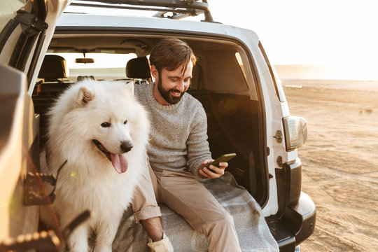 Handsome young bearded man sitting in the back of his car - Powered by Adobe