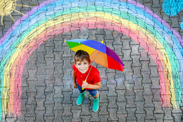 Happy kid boy in rubber boots with rainbow sun and clouds with rain drops painted with colorful...