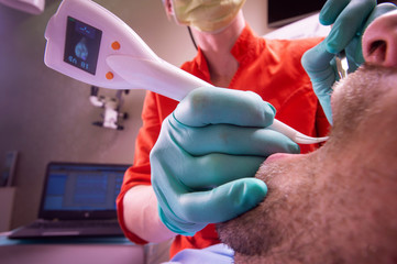 Automatic Digital Periodontitis detector being used on patients teeth for diagnosing periodontal...