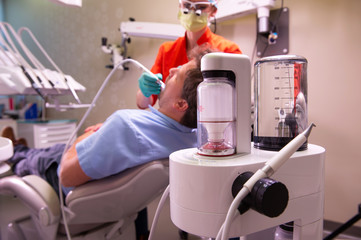 Patients teeth being cleaned with modern air pressure technology. Pressurised jet of air, water and powder removes surface stains, plaque and other soft deposits trapped in between the teeth.