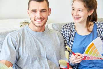 Paar als Heimwerker mit Pinsel und Farbfächer