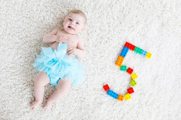 Adorable baby girl on white background wearing turquoise tutu skirt. Cute little child laughing and smiling. Happy carefree baby. Childhood, new life concept © Irina Schmidt