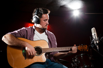 Front view man playing guitar and wearing headphones
