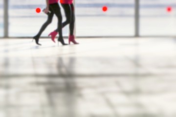 Defocused image of close up legs of two women walking silhouette on gray background