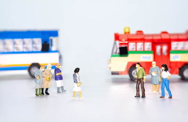 miniature figure doll people wearing face mask  to protect Coronavirus or Covid-19 with bus in back...