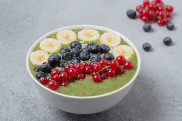 Breakfast detox green smoothie from kiwi, banana, spinach, red currant and blueberries in the bowl.
