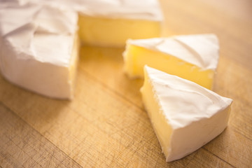 Camembert cheese with two slices triangles on a wooden board