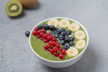 Breakfast detox green smoothie from kiwi, banana, spinach, red currant and blueberries in the bowl.
