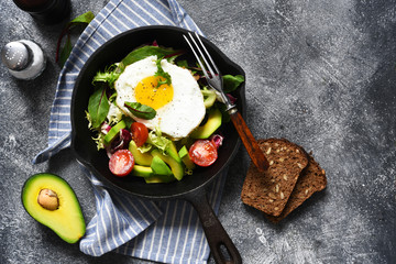 Salad with tomatoes and avocado, fried in a pan for breakfast.
