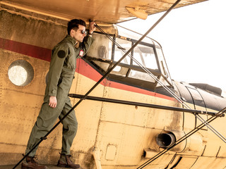 A handsome young pilot standing on the wing of a plane