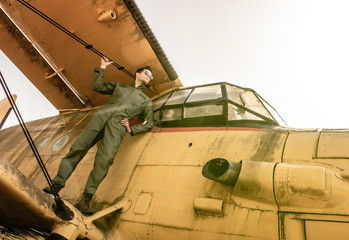 A handsome young pilot standing on the wing of a plane