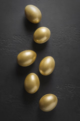 Chicken golden eggs on black. Easter dark concept. View from above.