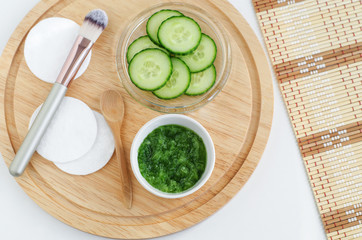 Fresh cucumber puree, cucumber slices, cotton pads and cosmetic brush. Ingredients for preparing homemade mask. Natural beauty treatment recipe and zero waste concept. Top view, copy space.  