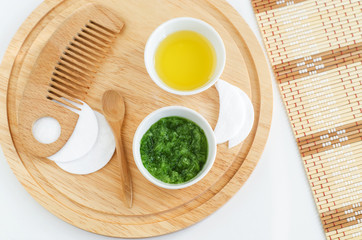 Fresh cucumber puree, olive oil, cotton pads and wooden hair comb. Ingredients for preparing homemade mask. Natural beauty treatment recipe and zero waste concept. Top view, copy space.  