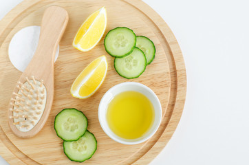 Olive oil, cucumber slices, lemon, cotton pad, wooden hairbrush. Ingredients for preparing homemade face and hair mask. Natural beauty treatment recipe and zero waste concept. Top view, copy space. 