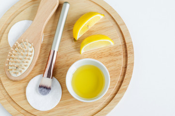 Olive oil, lemon slices, cotton pad, cosmetic brush and wooden hairbrush. Ingredients for preparing homemade mask. Natural beauty treatment recipe and zero waste concept. Top view, copy space. 