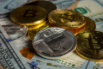 Gold and silver coins in the form of cryptocurrency on a pile of new-style hundred-dollar banknotes