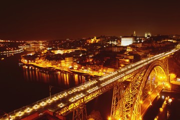 Fototapeta na wymiar Vista nocturna de la desembocadura del río Douro a su paso por las ciudades de Oporto y Vila Nova de Gaia en Portugal y del famoso puente Don Luis I que las comunica.