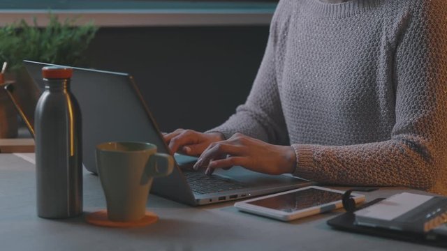 Woman sitting at desk and typing with her laptop