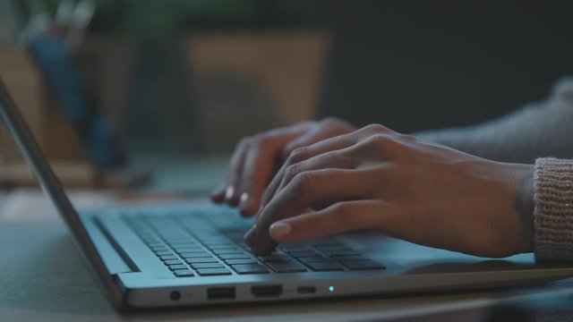 Woman sitting at desk and typing with her laptop - Powered by Adobe