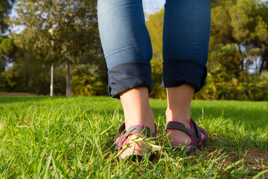 Woman In Sandals Walking On Green And Long Grass