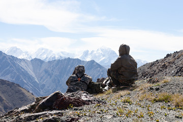 Hunter and huntsman in camouflage inspect the mountainous area.