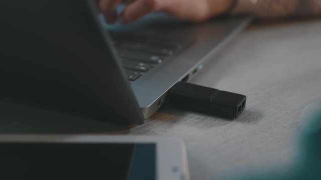 Woman plugging a USB flash drive into a laptop