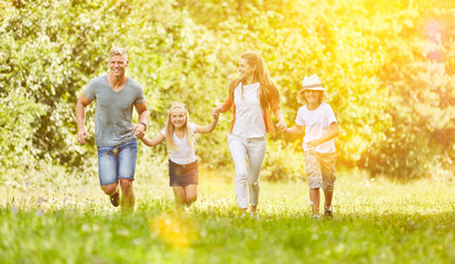 Fototapeta na wymiar Familie und Kinder laufen im Sommer in Natur