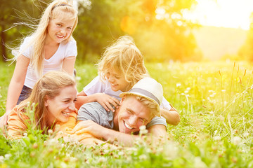 Familie liegt im Sommer auf Wiese im Urlaub