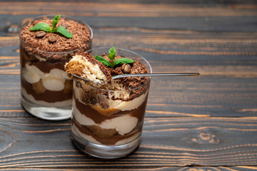 Classic tiramisu dessert in a glass cup on wooden background