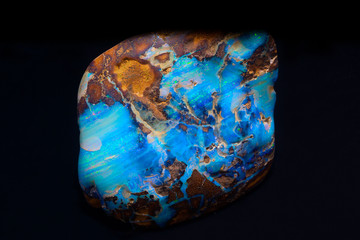 Piece of Australian boulder opal on black background.