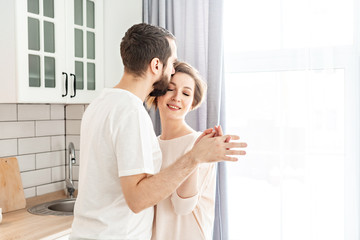 Happy romantic couple dancing in modern bright kitchen at home