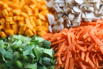 Chopped carrots, leek, red kuri squash and portobello mushroom on a wooden cutting board. Selective focus.
