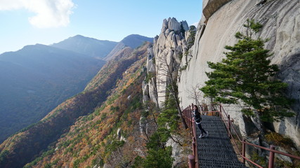 Woman tourist and a panoramic view from the Ulsanbawi rock to the landscape with an autumn forest...