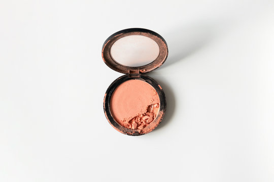 Broken crushed compact blush nude peach color on white background with copy space, top view. Simplicity beauty photo of decorative cosmetic