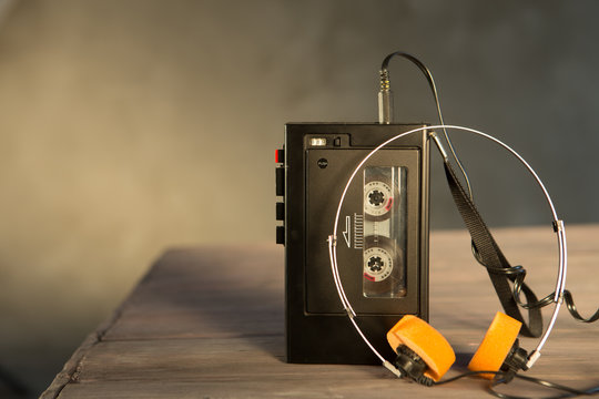 Old portable cassette player and headphones on a wooden background