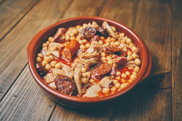 Garbanzos con callos en plato cerámico fondo madera
