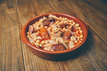 Garbanzos con callos en plato cerámico fondo madera